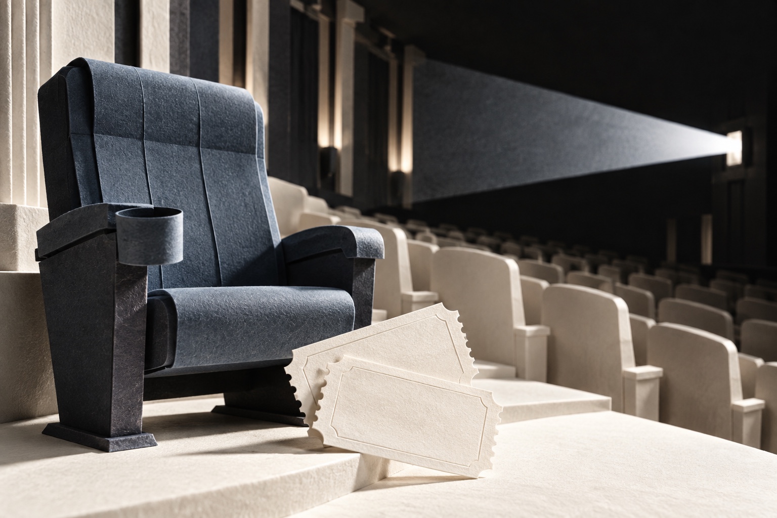 A slate paper-sculpture cinema seat, two ivory admission tickets and a projector beam across an auditorium.